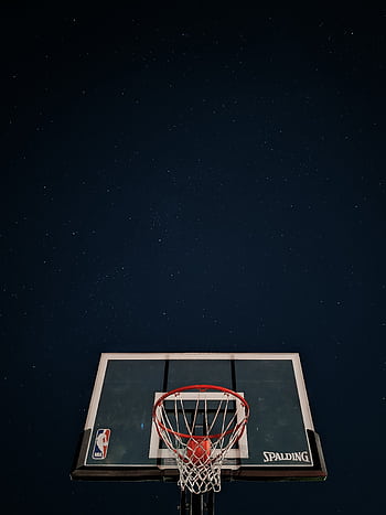 A basketball hoop silhouetted against a dark night sky filled with stars. HD phone wallpaper