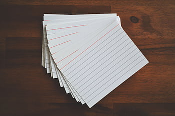 High-angle view of blank index cards arranged neatly on a wooden desk, ideal for education and organization concepts. HD wallpaper