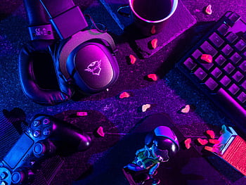 Colorful flat lay of gaming gear including headset, controller, and keyboard under vibrant lighting. HD wallpaper
