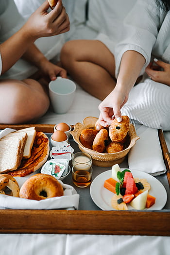 Relaxing morning in bed with coffee, assorted pastries, and fresh fruit on a wooden tray. HD phone wallpaper