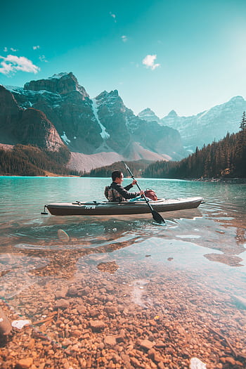 A lone kayaker paddles on the serene waters of Moraine Lake with stunning mountain scenery in Banff, Alberta. HD phone wallpaper