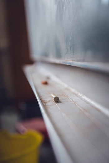 Dusty chalk resting on chalkboard ledge creating educational atmosphere. HD phone wallpaper