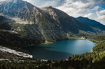 Breathtaking view of a serene mountain lake surrounded by lush forests and majestic peaks. HD wallpaper