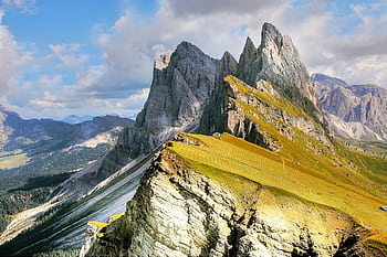 A breathtaking view of jagged mountain peaks and lush valleys under a vibrant blue sky. HD wallpaper