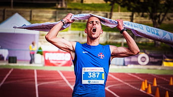 Athlete celebrates victory at marathon finish line triumphantly raising tape overhead. HD wallpaper