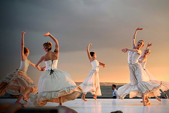 Elegant ballerinas performing a captivating dance at sunset outdoors. HD wallpaper