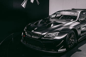 Black BMW racing car displayed in a Munich exhibition, showcasing modern automotive design. HD wallpaper