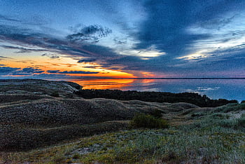 Beautiful sunset over ocean and hills with vibrant sky reflecting in water. HD wallpaper