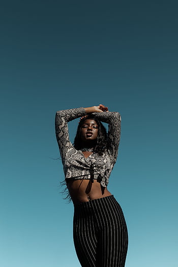 Elegant portrait of a fashionable black woman posing outdoors against a clear sky. HD phone wallpaper