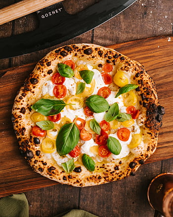Top view of a delicious Neapolitan pizza with vibrant cherry tomatoes and basil leaves. HD phone wallpaper