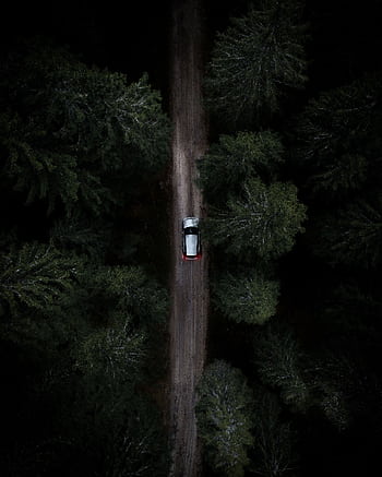 A lone car travels through a dense, dark forest. Aerial view capturing the mood of a secluded road journey. HD phone wallpaper
