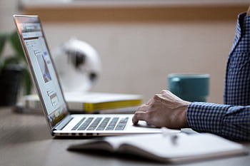 Business professional working on laptop at an office desk with coffee mug. HD wallpaper