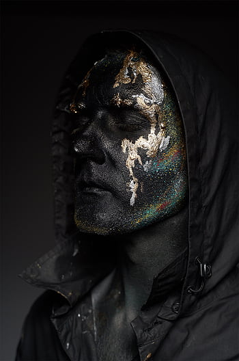 Close-up of a man with glittery face paint wearing a dark hoodie, expressing an eerie artistic style. HD phone wallpaper