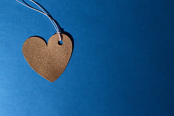 Heart-shaped cardboard cutout with string on a vivid blue background, symbolizing love. HD wallpaper