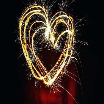 A heart shape created with sparklers, glowing brilliantly against a dark background. HD phone wallpaper
