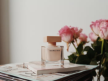 Sophisticated Narciso perfume bottle with pink roses and magazines. Perfect for elegance and fragrance themes. HD wallpaper