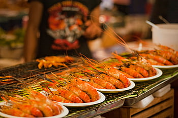 Deliciously grilled shrimps on plates ready to serve at a vibrant Bangkok street food market. HD wallpaper