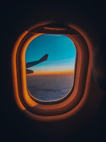 Experience the serene view from an airplane window overlooking a sunset sky and ocean horizon. HD phone wallpaper