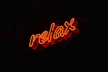 A glowing red neon 'relax' sign against a black background, perfect for modern decor. HD wallpaper