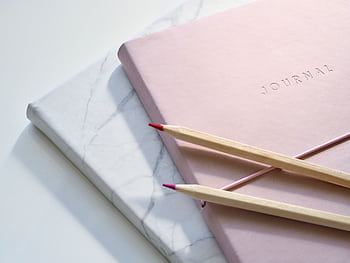 Close-up of a pink journal with pencils on a marble top. Perfect for note-taking or planning. HD wallpaper