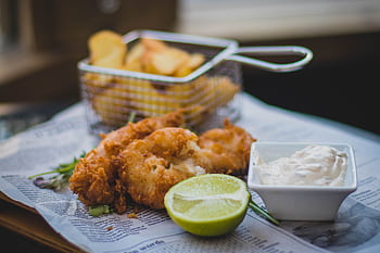 Close-up of fried fish and chips with tartar sauce and lime, perfect for food lovers. HD wallpaper
