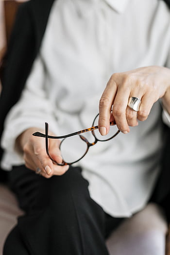 Close-up of a woman holding glasses, symbolizing thought and professionalism. HD phone wallpaper