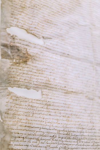 Close-up of a vintage manuscript showing weathered, torn edges and cursive calligraphy. HD phone wallpaper