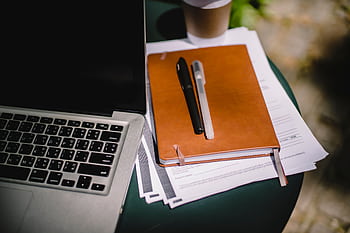 Overhead view of a workspace with a laptop, notebook, and coffee cup on an outdoor table. HD wallpaper