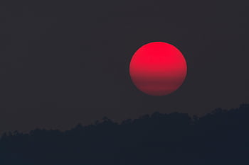 A captivating blood moon rising over a silhouette of hills, capturing the beauty of twilight. HD wallpaper