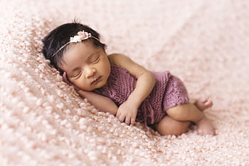 A newborn baby girl peacefully sleeps on a soft pink blanket, embodying innocence and tranquility. HD wallpaper