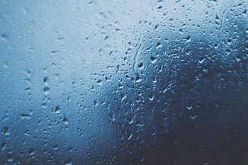 Detailed view of water droplets on a glass window with a blue background. HD wallpaper