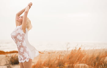 Woman in a white dress feeling by the beach during the day. HD wallpaper