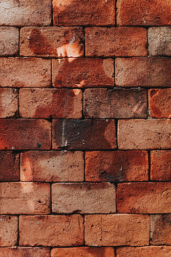 A detailed view of a weathered red brick wall showcasing rustic textures and shadows. HD phone wallpaper