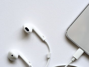 Minimalist top view of white wired ears connected to a smart on a clean white background. HD wallpaper