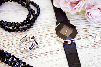 Close-up of luxurious black jewelry and watch with pink flowers on a wooden surface. HD wallpaper