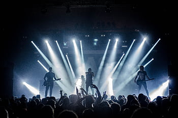 Energetic live concert with musicians performing on stage, engaging the crowd with vibrant lighting effects. HD wallpaper