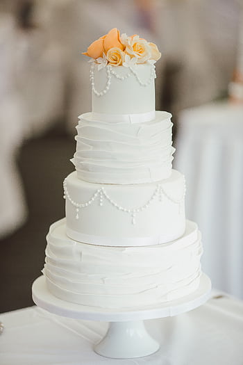 A sophisticated three-tier white wedding cake adorned with peach roses and pearl decorations. HD phone wallpaper