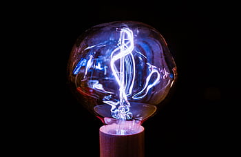 Close-up of a glowing vintage light bulb with an intricate filament design against a dark background. HD wallpaper