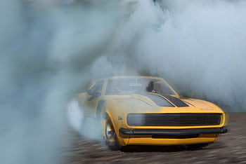 1969 Camaro drifting on pavement with smoke engulfing the car, showcasing its power. HD wallpaper