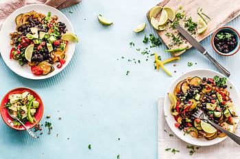 Colorful Mexican salad with avocado, black beans, and lime on a light blue surface. HD wallpaper