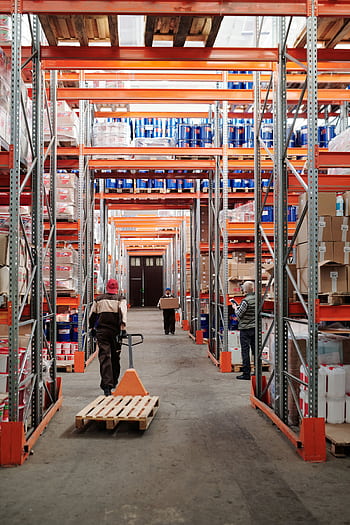 Workers arrange inventory on shelves in a large industrial warehouse. HD phone wallpaper