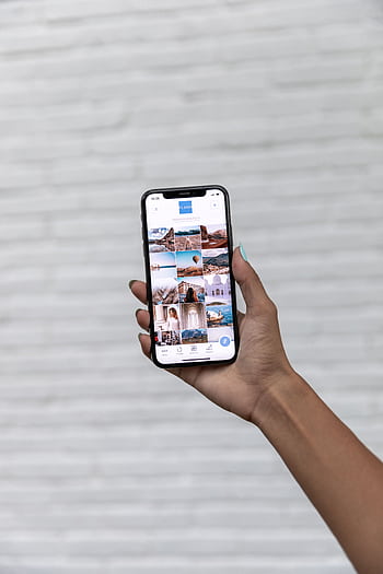 A hand holding a smart displaying travel against a white textured background. HD phone wallpaper