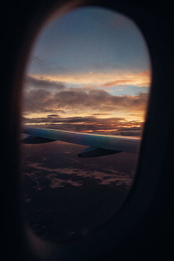 A scenic view of an airplane wing against a vibrant sunset sky, captured from a plane window. HD phone wallpaper
