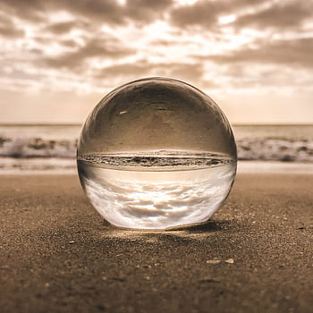 A glass sphere reflecting the sky and ocean on a sandy beach at sunset in Bonita Springs, FL. HD phone wallpaper