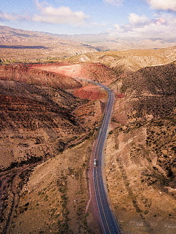 Stunning aerial shot of a tranquil highway winding through a desert landscape, capturing nature's grandeur. HD phone wallpaper