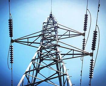 Low angle view of an industrial power transmission tower against a clear blue sky. HD wallpaper