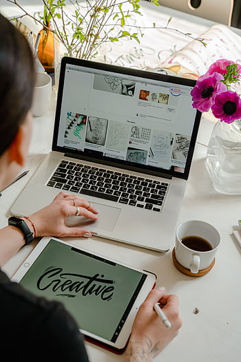 Creative work session featuring a woman using a tablet and laptop for design projects. HD phone wallpaper