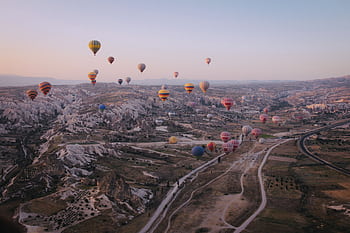 Hot air balloons floating over Cappadocia's unique landscape at sunrise. HD wallpaper