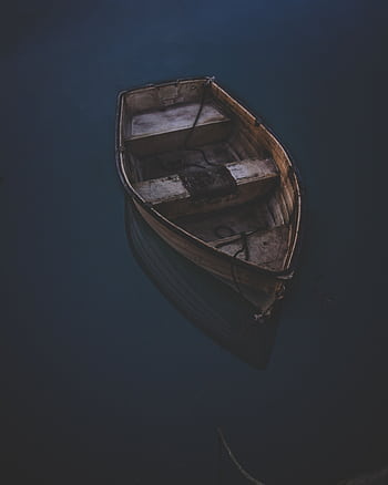 An isolated wooden boat gently floats on calm waters during twilight in West Bay, England. HD phone wallpaper