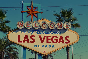 The famous Welcome to Las Vegas sign framed by palm trees under clear skies. HD wallpaper